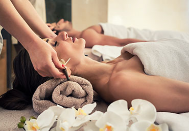Relaxed woman lying down on massage bed during facial treatment at Asian spa and wellness center